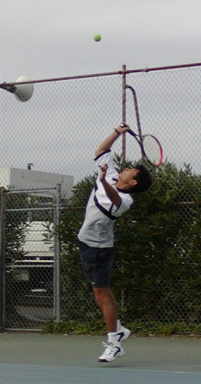 Ball Toss completed, and racket coming up from behind to reach for the ball.